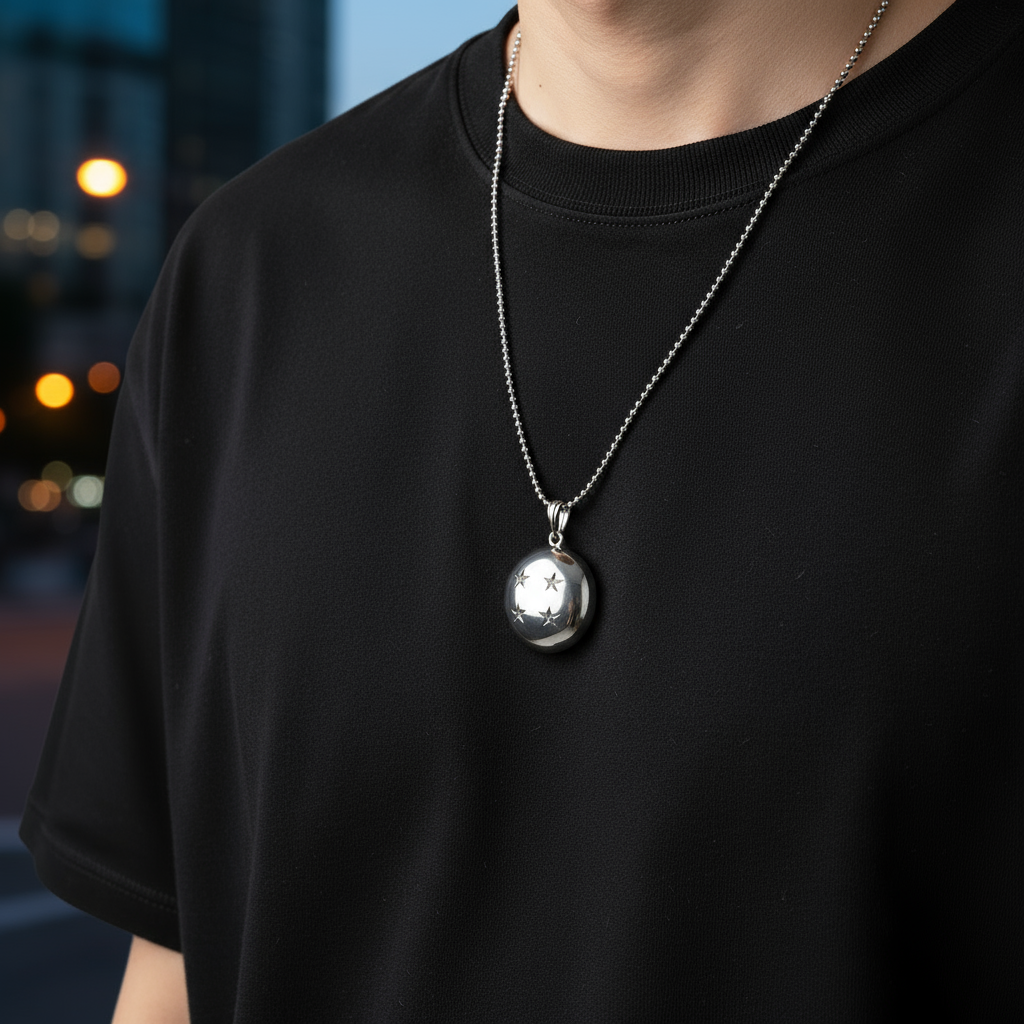 Person wearing a black t-shirt with a silver necklace featuring a round pendant.