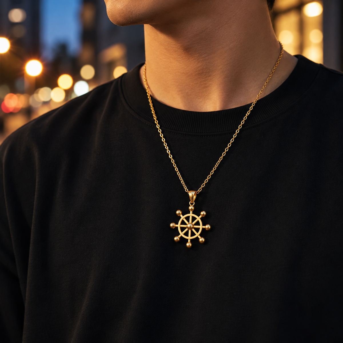 Person wearing a black shirt with a gold necklace featuring a wheel pendant against a blurred cityscape background.