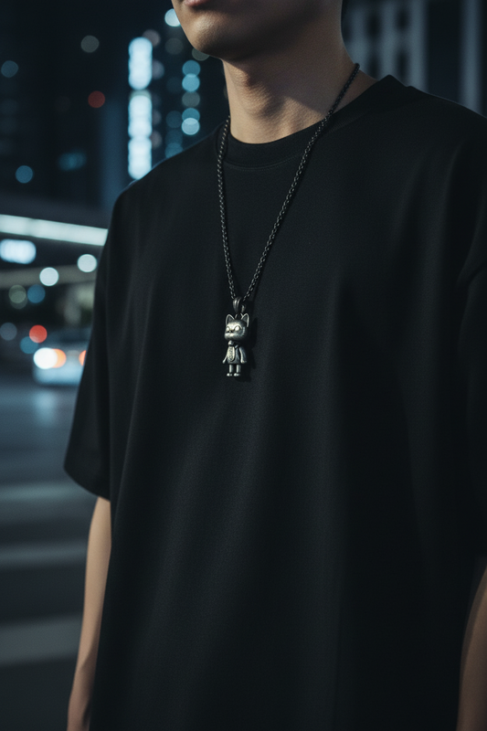 Person wearing a black t-shirt with a necklace featuring a pendant in an urban night setting.