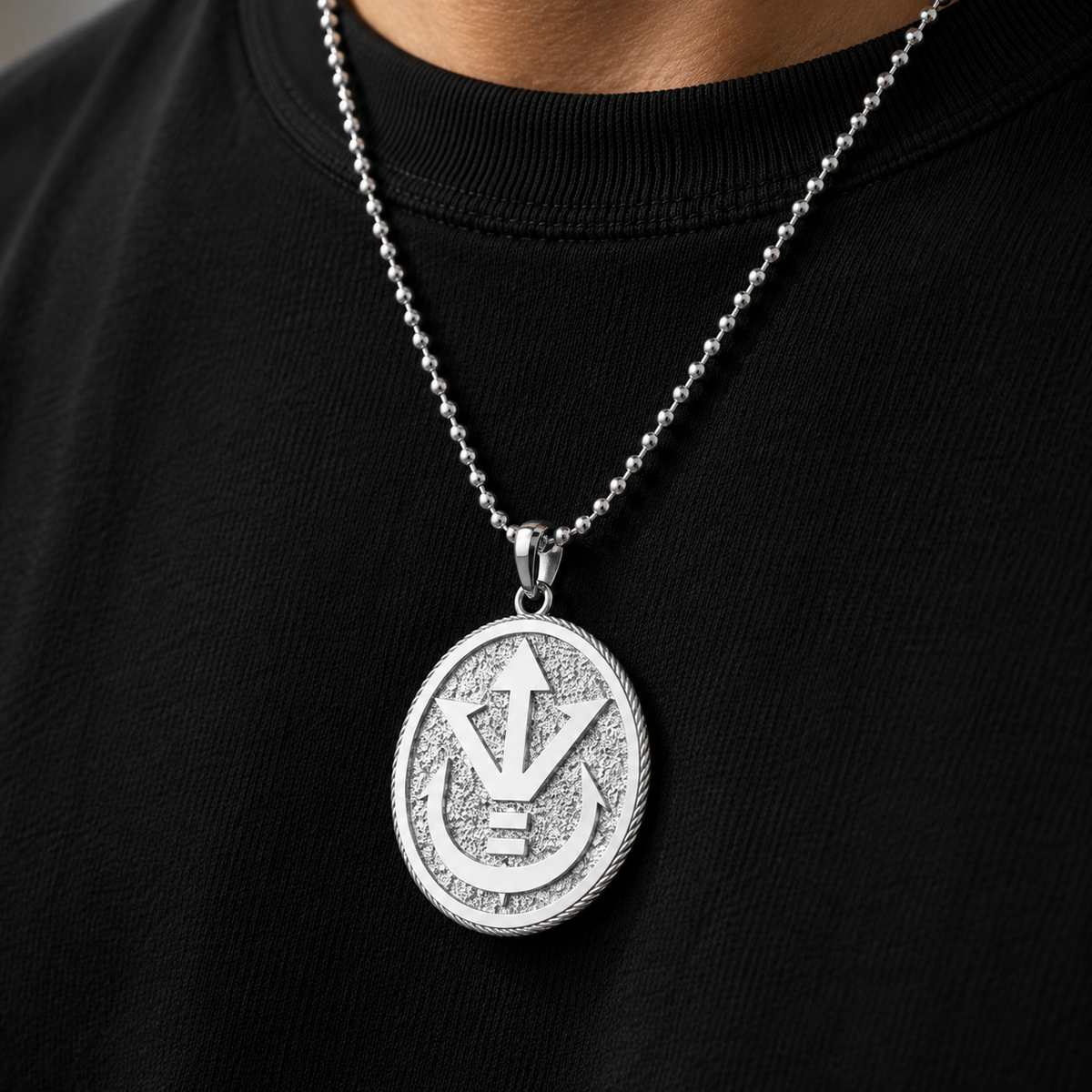 Person wearing a black shirt with a silver necklace featuring a round pendant.