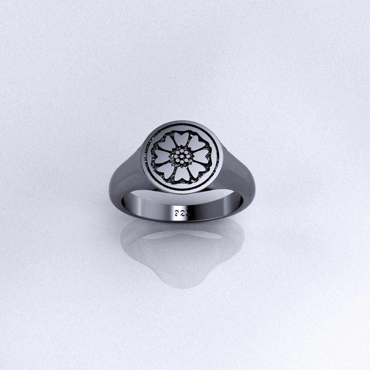 A silver signet ring with a lotus flower design, displayed against a backdrop with colorful abstract patterns.