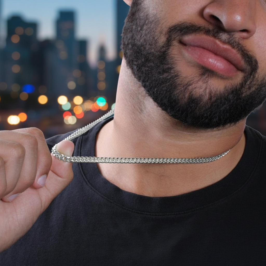 Man holding a silver chain necklace with a cityscape in the background