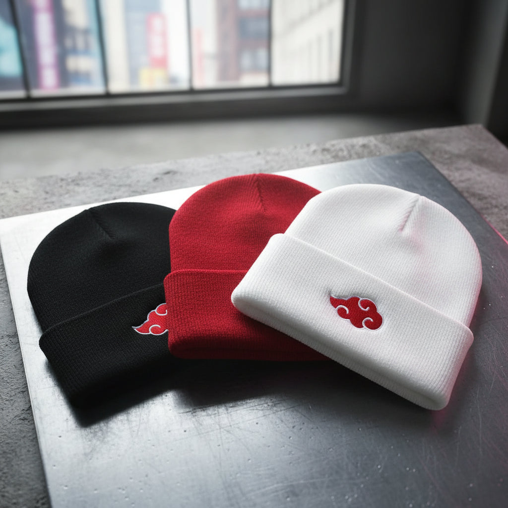Four beanies in black, red, white, and gray with a red cloud symbol on a wooden surface.