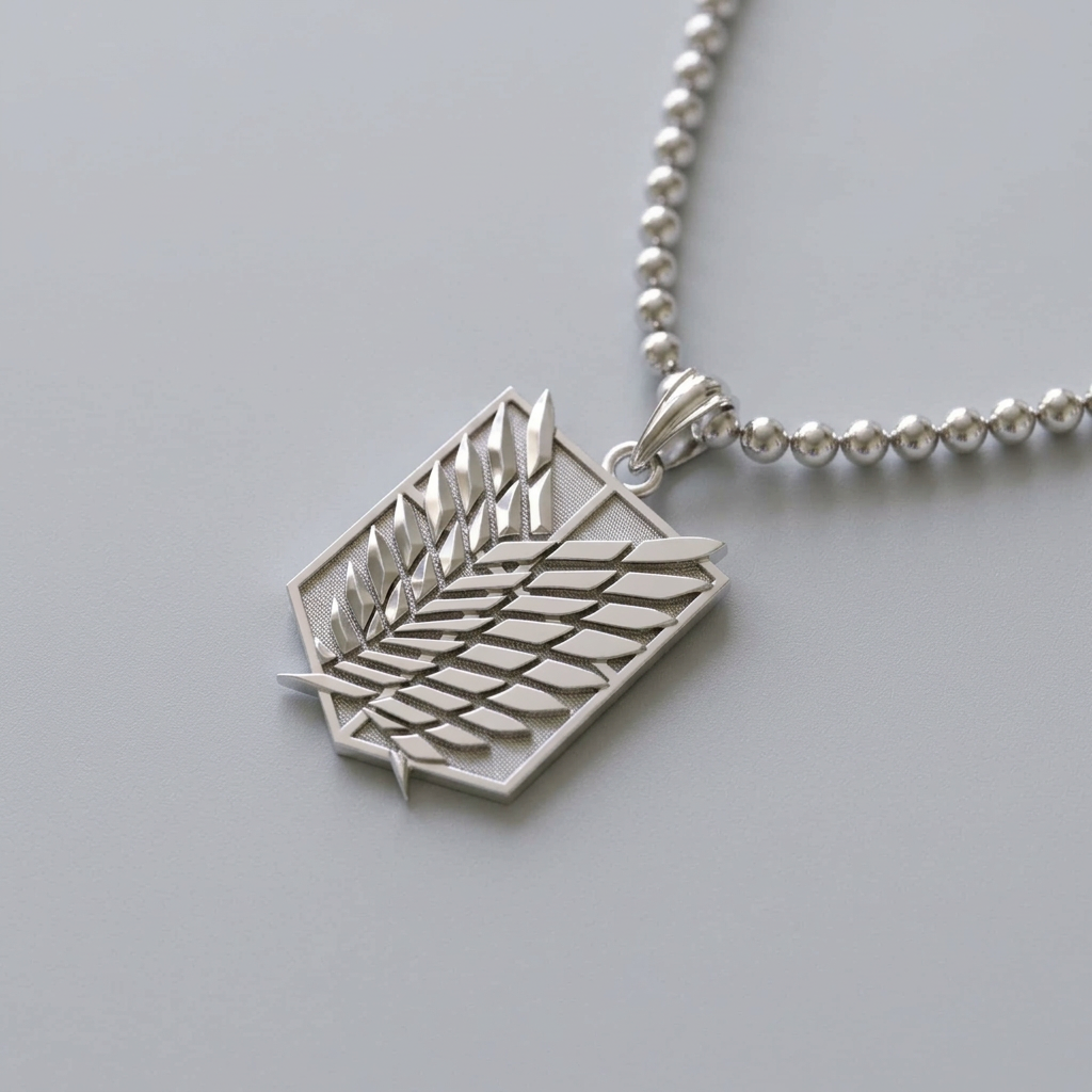 A silver pendant necklace featuring the Attack on Titan Survey Corps emblem, resting on a dark slate slab over a white marble surface.