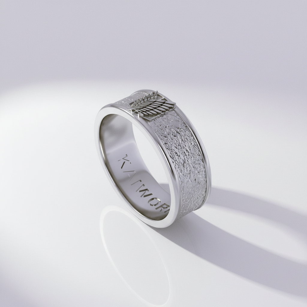 A silver ring with detailed wing design, set against a textured background featuring a silhouette of a character and the word 'ATTACK'.