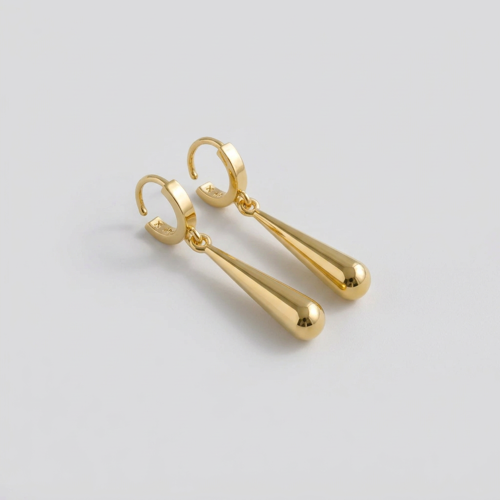 A set of three gold-colored earrings with a sword motif, placed on a wooden surface.