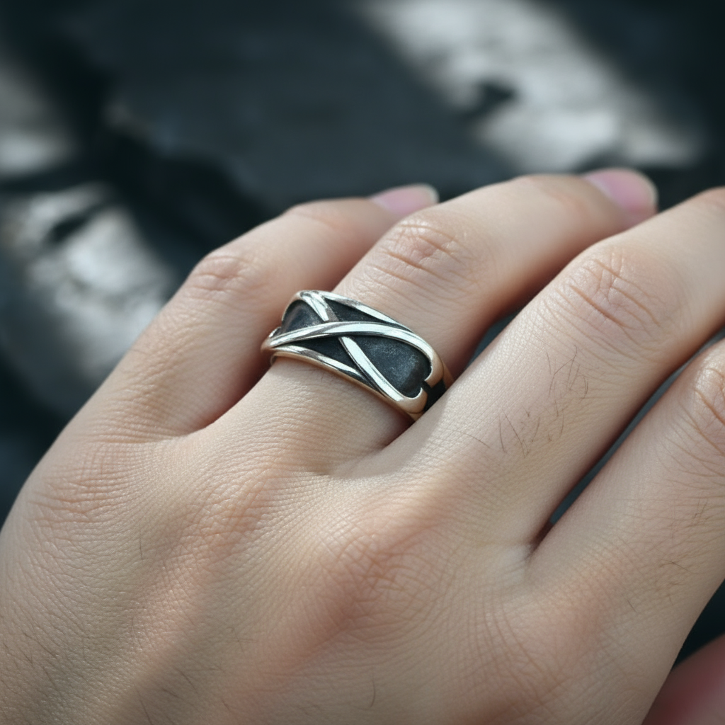 Silver ring with a unique design on a person's finger against a blurred background