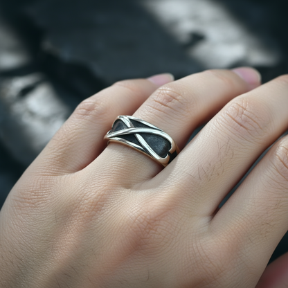 Silver ring with a unique design on a person's finger against a blurred background