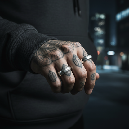 A stainless steel ring with the engraved text 'Sir Francis Drake 1596' and 'SIC' on the band, placed on a wooden surface with greenery in the background.