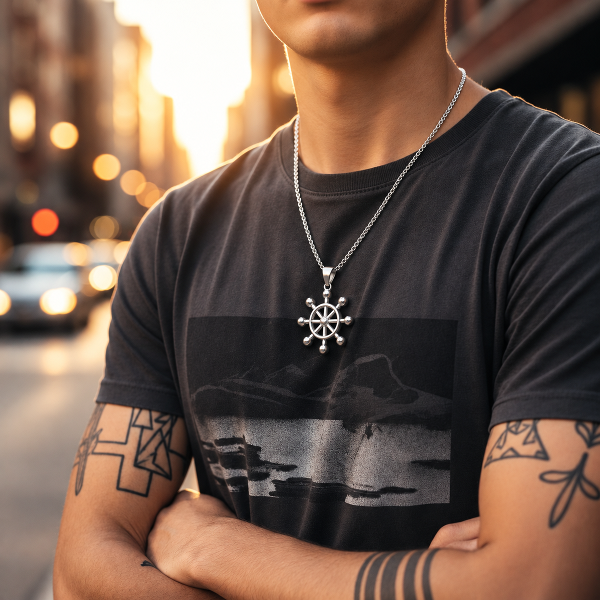 Man wearing a dark t-shirt with a graphic design and a necklace with a pendant, standing on a street.