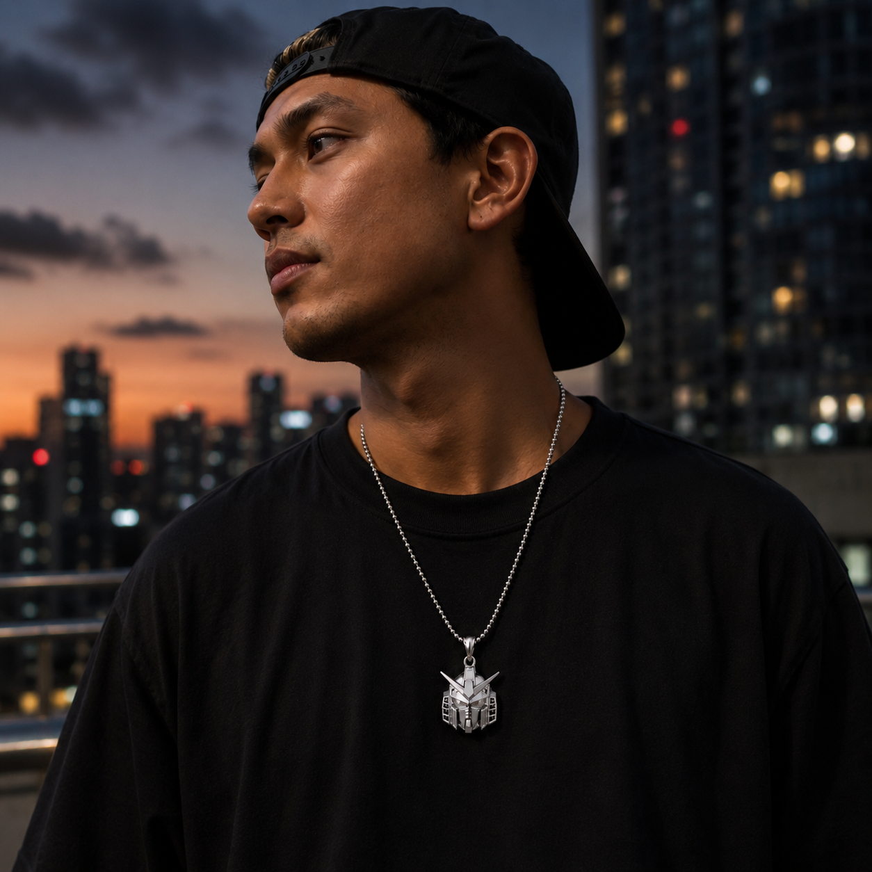 Man wearing a black cap and black shirt with a necklace, standing against a cityscape at dusk.
