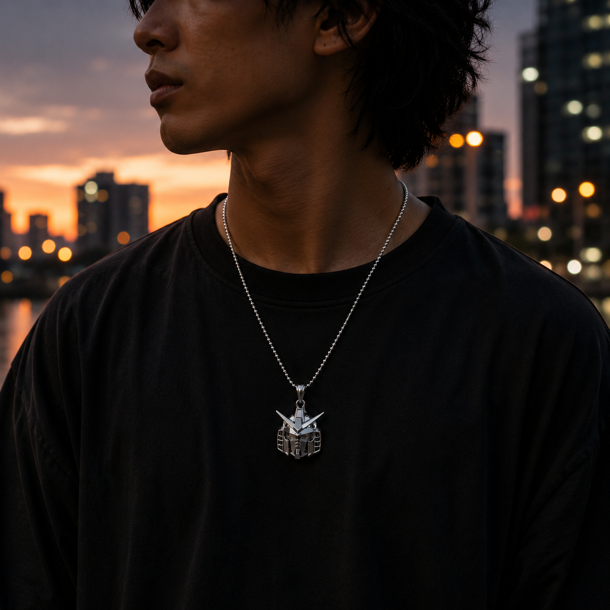 Person wearing a necklace with a pendant against a cityscape at sunset.