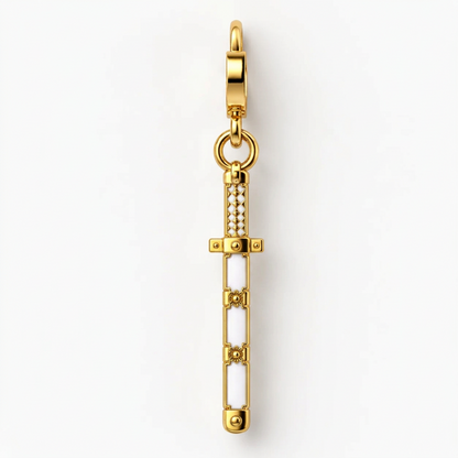 A gold-plated sword charm with white enamel inlay and small clear rhinestone accents, shown vertically on a clean white background.