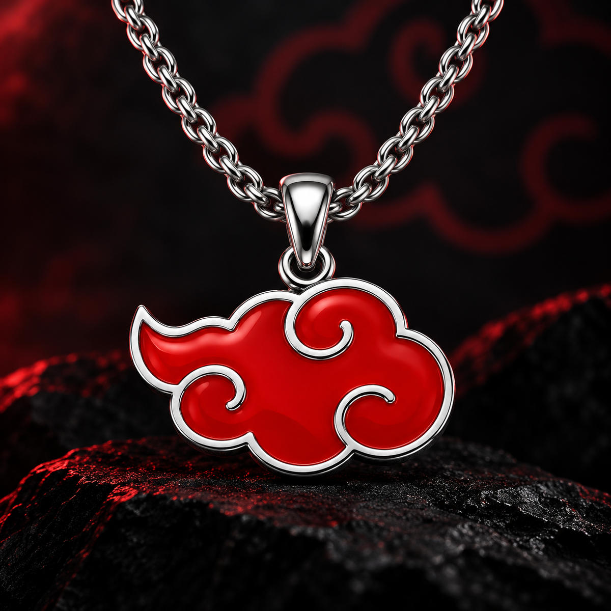 A silver-toned necklace with a red cloud-shaped pendant, styled on dark textured rocks against a dark red and black background.