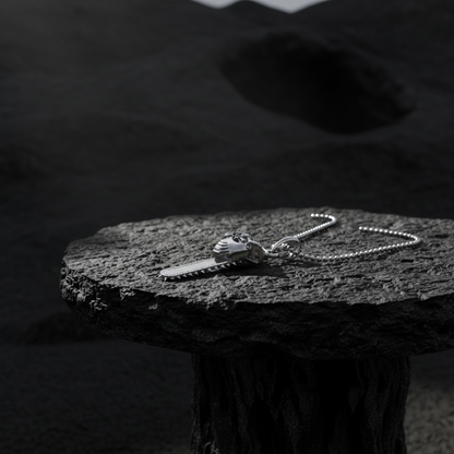 Silver necklace on a dark stone surface with a blurred natural background