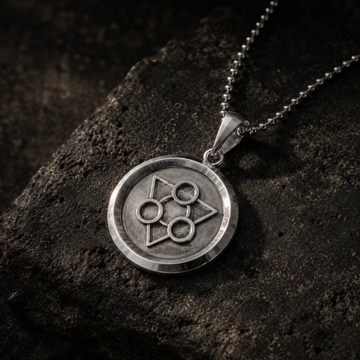 Silver pendant necklace with a unique design on a dark stone surface